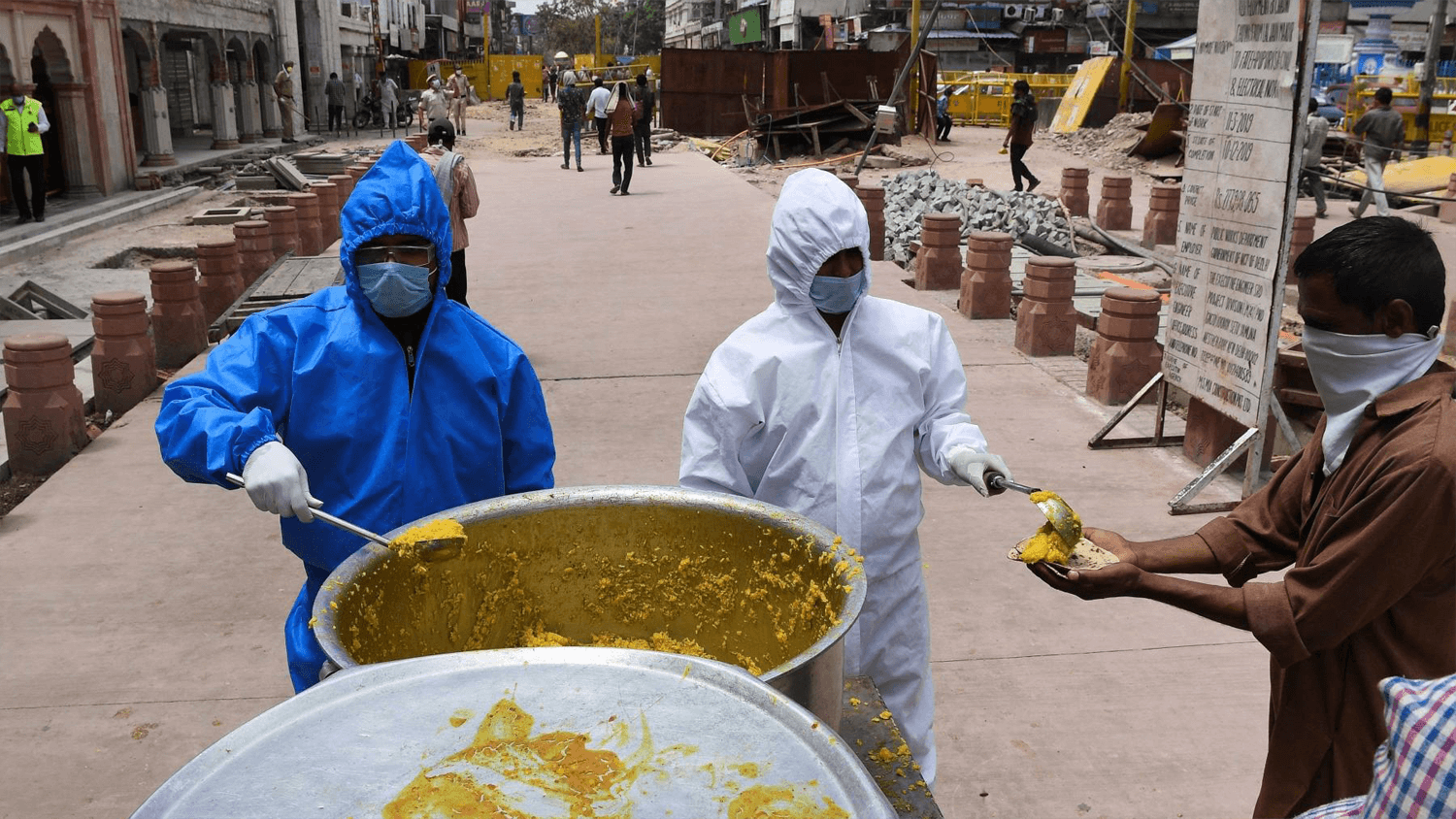 Workers in full PPE gear hand out food in India