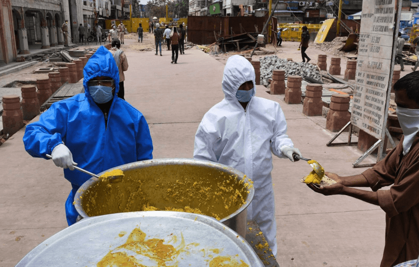 Workers in full PPE gear hand out food in India